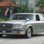 El Toyota Century es el epítome del lujo discreto. Nada de estridencias ni caballos desbocados: su V8 de 4.0 litros y 190 CV está pensado para una conducción extremadamente suave. Diseñado para transportar a altos dignatarios con serenidad, su interior ofrece tapicería de lana, climatización trasera oscilante y asientos reclinables. Más que un coche, el Century es un salón rodante y un monumento al refinamiento nipón.