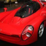 El Yamaha OX99-11 fue un intento ambicioso de Yamaha para trasladar su experiencia en la Fórmula 1 al mundo de los coches deportivos. Desarrollado en 1992, el OX99-11 utilizaba un motor V12 de Fórmula 1 y un chasis monocasco de fibra de carbono. Solo se fabricaron tres prototipos de este coche, lo que lo convierte en una pieza extremadamente rara y valiosa. Su diseño de asientos en tándem bajo un techo tipo capó ofrecía una experiencia de conducción única, pero el proyecto fue detenido debido a la recesión económica de Japón. A pesar de su corta existencia, el OX99-11 sigue siendo un sueño para los entusiastas del automovilismo.