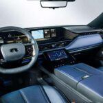 El interior del QX80 Sport es una combinación de lujo y tecnología. El tema bicolor en tonos azul grisáceo transmite una atmósfera sofisticada y moderna, donde los asientos de cuero semianilina azul y negro con perforaciones en patrón diamante destacan por su elegancia. El acabado en madera de fresno y los acentos cromados mate aportan profundidad y distinción al ambiente. Además, el sistema de iluminación ambiental de 64 colores y el revestimiento del techo en color grafito refuerzan la sensación premium de la cabina.
