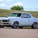 El Pontiac Tempest 326 de 1966 fue una versión más suave del GTO, con una apariencia similar pero con menos potencia. Su motor 326 V8 entregaba solo 250 caballos de fuerza, lo que lo hacía más adecuado para quienes buscaban el aspecto de un muscle car sin el rendimiento agresivo. El tiempo de ¼ de milla del Tempest fue de 16.7 segundos, una cifra bastante alejada de los competidores más rápidos de la época. La suspensión, con resortes de espiral en todas las ruedas, estaba más orientada al confort que a la agresividad, lo que lo convertía en una opción más tranquila en comparación con otros modelos.