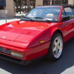 El Ferrari Mondial T es una opción intrigante que combina la practicidad de cuatro plazas con la elegancia del motor central. Gracias a su configuración ‘T’ (un motor V8 montado longitudinalmente y una caja de cambios transversal de 5 marchas), este modelo supera a muchos de sus rivales de coupe en cuanto a rendimiento, mientras que su precio se mantiene más accesible.
Con un valor promedio entre los $30,000 y los $70,000, el Mondial T ofrece una opción asequible para los que buscan un Ferrari con espacio para los amigos y una conducción divertida. Además, su estilo angular de los años 80 evoca nostalgia de los icónicos días de Miami Vice.