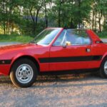 Con motor central y diseño de Bertone, el Fiat X1/9 ofrece una arquitectura propia de coches exóticos a precios sorprendentemente contenidos. Su comportamiento dinámico es ágil y comunicativo, ideal para quien valora el paso por curva más que la potencia bruta. Es un coche que conecta directamente con la filosofía de ligereza y equilibrio tan valorada también en la Fórmula 1 clásica.