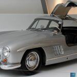 El Mercedes-Benz 300 SL es una obra maestra de ingeniería y diseño de posguerra. Famoso por sus puertas de apertura vertical, fue el coche de producción más rápido de su época. Su chasis tubular obligó a adoptar esta solución tan icónica. Equipado con un motor de seis cilindros y tecnología de inyección directa, era tan avanzado como exclusivo. El 300 SL simboliza el renacimiento de Mercedes-Benz tras la Segunda Guerra Mundial y sigue siendo uno de los clásicos más deseados del mundo. Su valor histórico y estético lo convierten en una pieza imprescindible para cualquier gran colección.
