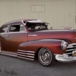 El Chevy Fleetmaster '48 fue uno de los primeros lowriders, conocido como “bomb”. Su motor de seis cilindros en línea de 216 pulgadas cúbicas y 90 caballos de fuerza era suficiente para convertirlo en lienzo sobre ruedas. Mexican Americans aplicaron sus habilidades mecánicas para crear vehículos únicos, estableciendo el estilo que definiría la cultura lowrider durante décadas.