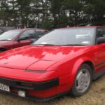 El MR2 AW11 ofrece un esquema de motor central a un precio inferior al de muchos deportivos similares. Con motor 1.6L 4A-GE de 112 CV, se centra en la conducción y no en la velocidad máxima. Su tamaño compacto y peso reducido mantienen los costes bajos. Ejemplares originales y en buen estado se venden entre 7.800 y 15.000 dólares.