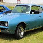 Su empuje brutal se combinaba con muelles y amortiguadores blandos, provocando gran balanceo y chasis lento en asentarse. Los frenos de la época y la dirección orientada al confort hacían que el frontal se abriera en curvas mientras la carrocería oscilaba.