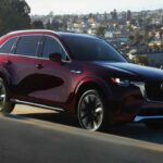 El Mazda CX-90 2026 se distingue por su enfoque en la dinámica de conducción, sin perder la capacidad de ofrecer un espacio adecuado para la familia. Su motor de seis cilindros en línea proporciona una potencia suave y refinada, mientras que la tracción total (AWD) de serie le otorga un manejo superior en diversas condiciones. Con un diseño interior cuidadosamente detallado y un rendimiento que se siente más cercano al de un coche de lujo, el CX-90 ofrece una experiencia de conducción envolvente y elegante, ideal para quienes buscan algo más que un simple SUV.