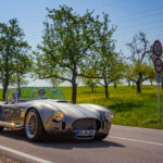 Carroll Shelby tomó un roadster británico ligero y le instaló un enorme V8 americano. El par descomunal, la suspensión rudimentaria y neumáticos estrechos hacían que el coche fuera casi indomable, intimidante incluso para pilotos con experiencia.