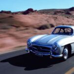 El Mercedes-Benz 300 SL Gullwing es considerado por muchos como el primer superdeportivo de la historia. Equipado con un innovador motor de seis cilindros en línea de 3.0 litros con inyección de combustible, desarrollaba 215 CV y alcanzaba los 261 km/h. Su chasis tubular ultraligero y sus icónicas puertas “alas de gaviota” no solo marcaron un antes y un después en diseño, sino también en ingeniería.