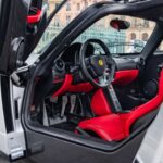 Este ejemplar, chasis 37754, es uno de solo cinco Enzo pintados en color plata con interior Rosso. Más exclusivo aún: es el único con esta combinación entregado en el Reino Unido. Incorpora detalles especiales como asientos de gran tamaño, arneses de cuatro puntos y cuentarrevoluciones en rojo, elementos que refuerzan su carácter de pieza de colección.