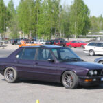El BMW M5 E28 cambió para siempre el mundo de las berlinas deportivas. Hasta su llegada, parecía imposible combinar lujo, confort y prestaciones de auténtico deportivo en un mismo coche. BMW rompió todas las reglas utilizando un motor derivado directamente del mítico BMW M1 y creando la berlina de cuatro puertas más rápida de su época. Su seis cilindros de 3.5 litros y 286 caballos permitía alcanzar 250 km/h y ofrecía unas prestaciones que humillaban a muchos deportivos exóticos de mediados de los 80. Además, su diseño discreto lo convertía en un auténtico “lobo con piel de cordero”.