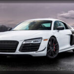 El Audi R8 supuso una auténtica revolución para la marca de los cuatro aros. Inspirado en los prototipos ganadores de las 24 Horas de Le Mans, debutó en 2006 con un motor V8 atmosférico de 4,2 litros y 414 caballos. Más adelante recibió el espectacular V10 de 5,2 litros derivado de Lamborghini, convirtiéndose en uno de los superdeportivos más completos de su generación. Su combinación de prestaciones, facilidad de conducción y fiabilidad le permitió competir frente a Ferrari y Porsche con argumentos propios.
