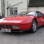El Ferrari 328 tomó todo lo que hizo famoso al Ferrari 308 y lo refinó prácticamente en cada apartado. Equipado con un V8 atmosférico de 3.2 litros y alrededor de 270 caballos, era capaz de acelerar de 0 a 100 km/h en unos 5,5 segundos y superar los 260 km/h. Pero más allá de las cifras, el 328 destacó por ofrecer una conducción más suave, fiable y utilizable que otros Ferrari anteriores. Su diseño firmado por Pininfarina sigue siendo una referencia absoluta de la estética italiana de los años 80, especialmente en la versión GTS con techo desmontable.