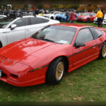 El Pontiac Fiero sorprendió al mercado estadounidense al ofrecer una configuración de motor central a un precio relativamente asequible. Su producción entre 1984 y 1988 estuvo marcada por problemas iniciales de calidad que dañaron su reputación, aunque las versiones posteriores mejoraron notablemente. Con el tiempo, los aficionados han sabido valorar su diseño innovador y su enorme potencial para modificaciones de alto rendimiento.