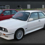 El BMW M3 E30 marcó un antes y un después en el segmento de las berlinas deportivas. Desarrollado inicialmente para homologar el modelo de competición, destacaba por su ligero peso, su motor de altas revoluciones y una dinámica de conducción excepcional. Sus éxitos en los campeonatos de turismos consolidaron una reputación que continúa creciendo entre los aficionados.