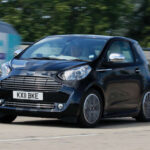 El Aston Martin Cygnet surgió como respuesta a las exigentes normativas de emisiones de CO₂. Basado en el Toyota iQ, cada unidad requería alrededor de 150 horas de trabajo artesanal para incorporar materiales y acabados propios de Aston Martin. Solo se fabricaron 786 unidades, lo que lo convierte en uno de los modelos más exclusivos y peculiares de la marca británica.